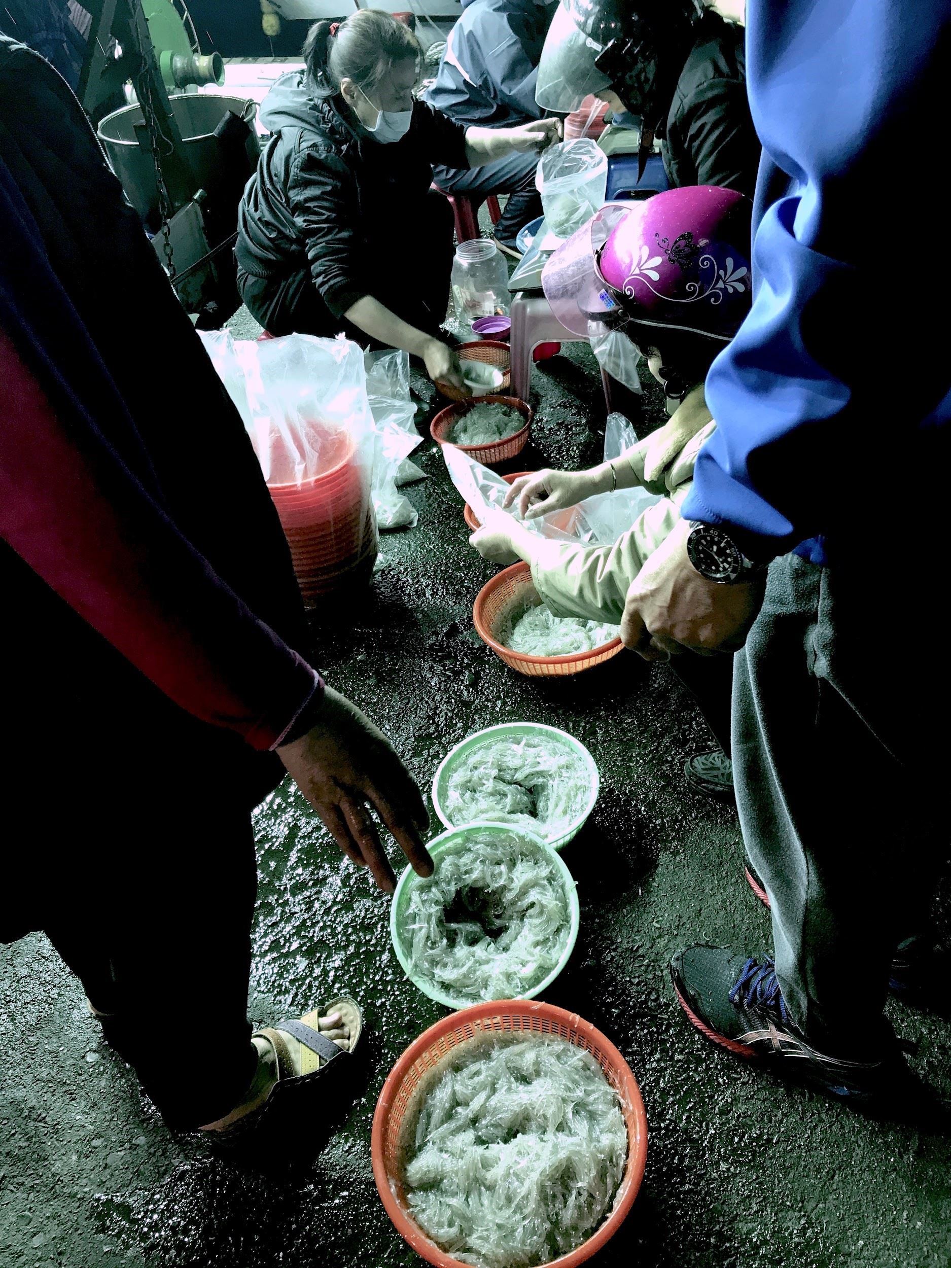 各自拿著籮筐排隊秤重，船家會幫忙分裝